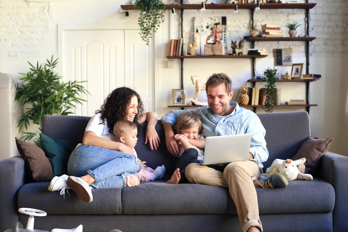 Family sitting on a sofa looking at a laptop