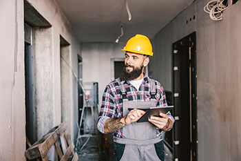 Man in hard hat surveying home project