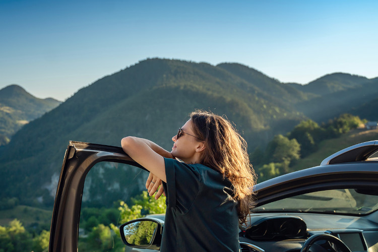 Person looking a green mountain view from their car