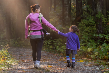 Mother and child holding hands while walking through trees