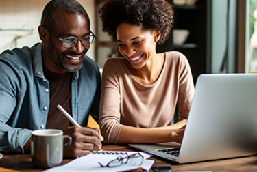 Two people sat at laptop with pen and paperwork