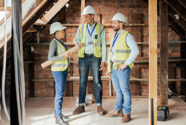 Workers in a home building site wearing high visibility clothing and safety hats